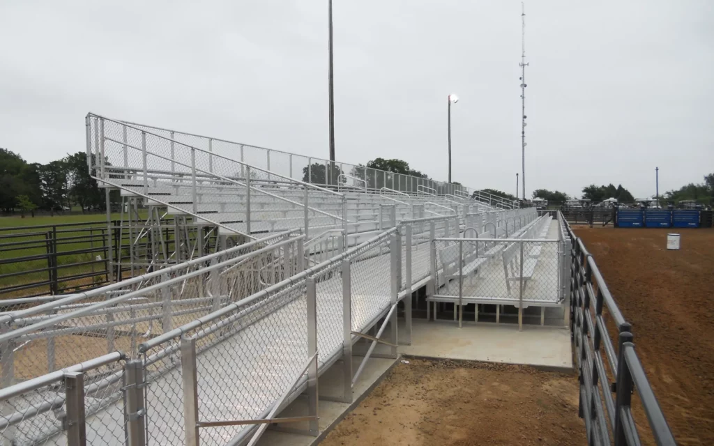 Outdoor elevated bleachers and walkway along dirt arena.